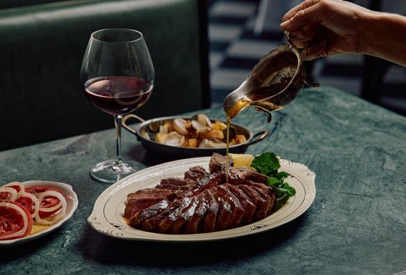 T-Bone Steak Pour, a plate of vegetables, tomato salad and red wine at Osteria Mucca, Sydney, New South Wales © Osteria Mucca