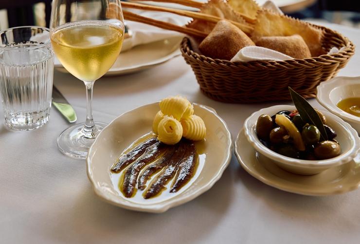 Anchovies & Butter, Pane, Marinated Olives and a glass of white wine at Osteria Mucca, Sydney, New South Wales © Osteria Mucca
