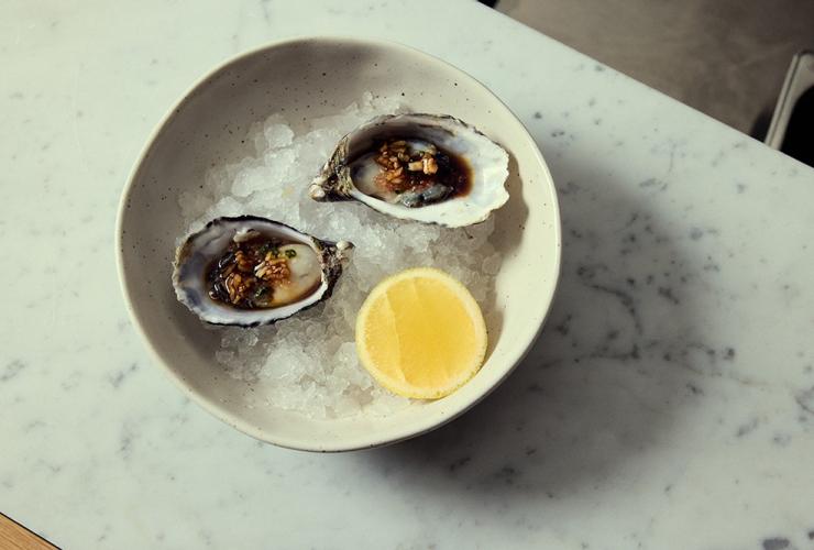 Two oysters in their shell with a finger lime mignonette at Haven, Mondrian, Gold Coast, Queensland © Content Lion