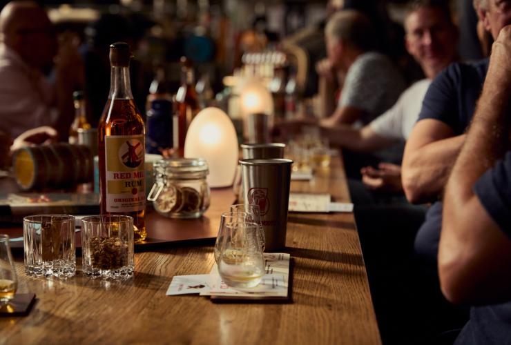 A bottle of Red Mill Rum on the table being enjoyed by a group © Red Mill Rum Distillery