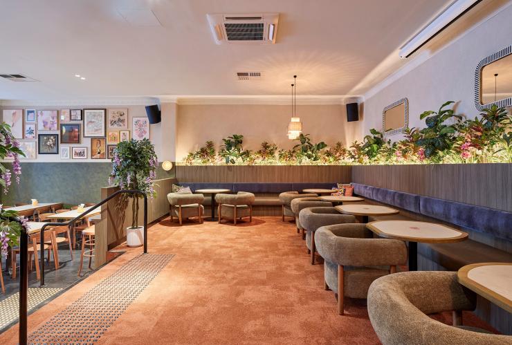 A view of Lil’s Hideout showing banquette seating, tables  and soft chairs on an upper level and tables and chairs below. © Shot by Thom