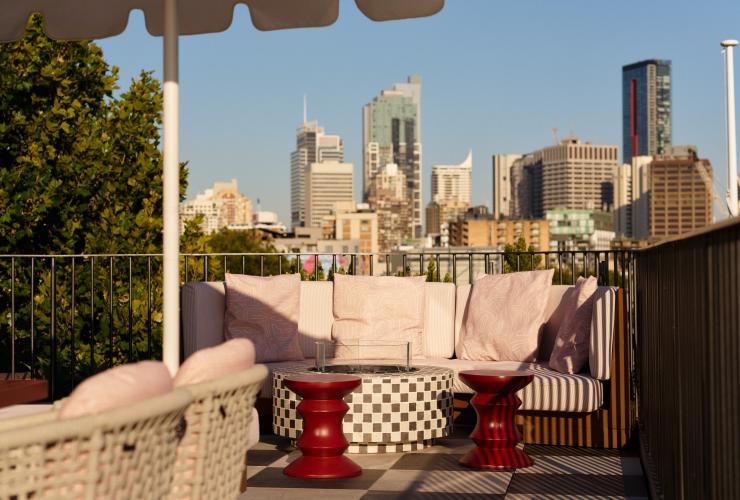 Soft sofa seating and umbrella for shade on the rooftop terrace at Monica with blurred city views as a backdrop. © Steven Woodburn