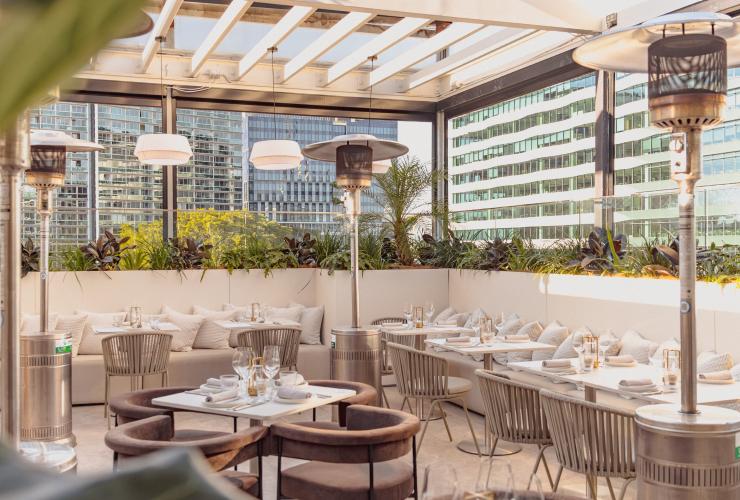 Banquette seating and tables set up for an event with the city in the background. © Siroco