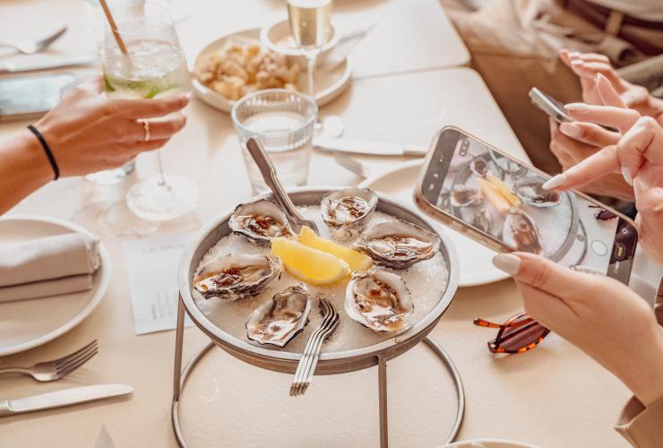 Oysters elevated on a stand filled with ice being captured on a guest’s iPhone. © Siroco
