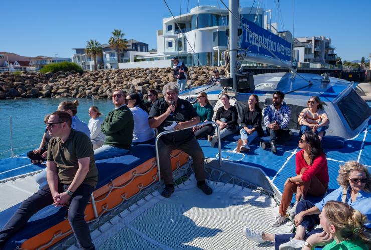 An Indigenous guide speaks to a group on the Temptation Sailing catamaran during the Kauwi Cultural Cruise © Temptation Sailing