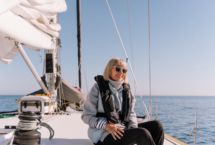 A happy guest sitting on the helm on Brindabella © Arne Studio