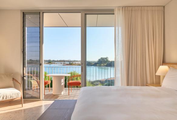 The interior of a poolhouse guestroom looking out over the balcony with a view to the lake. © Shot By Thom