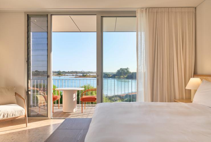 The interior of a poolhouse guestroom looking out over the balcony with a view to the lake. © Shot By Thom