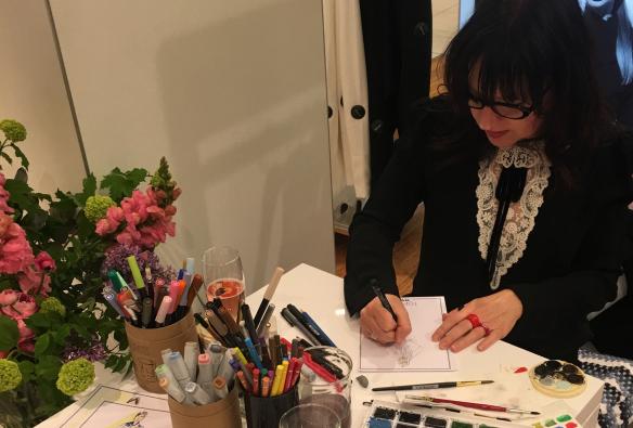 Artist Ange Rehe sits at a table at an event to create live portraits of delegates © Angie Rehe  