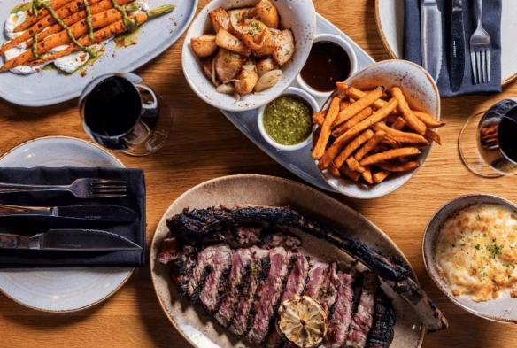 A table is set full of food fresh from a South African-inspired kitchen, steaks, potatoes, fries © 7 Cutz  