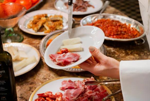 A waiter dishes out a serving of meats and cheeses from a charcuterie buffet © Roma Ristorante