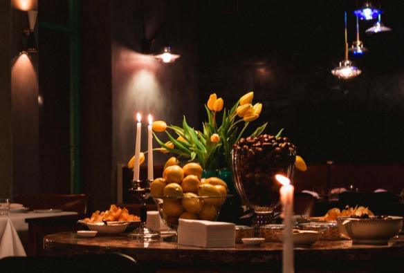 Candles, flowers and a bowl of lemons sit on a bar in a dimly lit restaurant © Roma Ristorante 