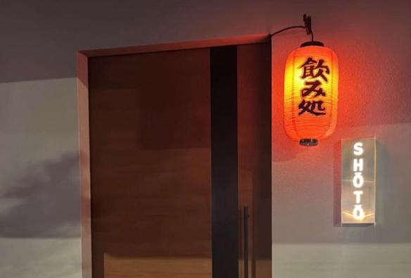 The wooden front door to a restaurant is marked with a red lantern and shiny silver sign © Shōtō
