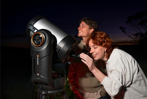 A person peers through the lens of a large, professional telescope, while another person looks up at the night sky © Blue Mountains Stargazing