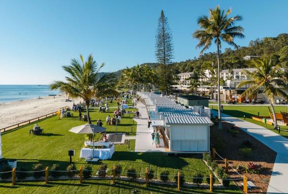 An aerial shot shows a row of white cabanas positioned on the grass just steps from the white sand and turquoise ocean water © Tangalooma Island Resort