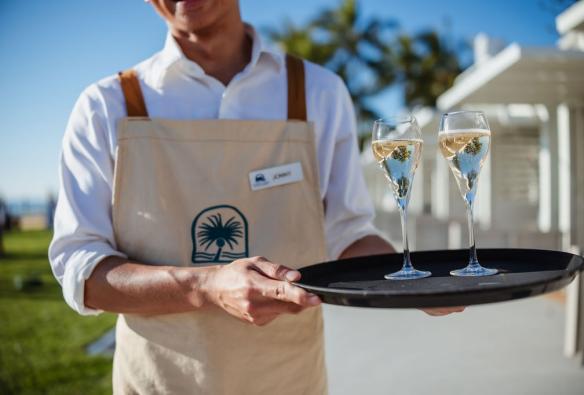 A close up of a staff member holding a tray with two glasses of sparkling wine © Tangalooma Island Resort