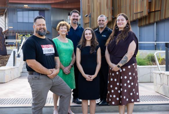 A group of six staff members stand outside the entry to a cultural building. © Larrakia Cultural Centre