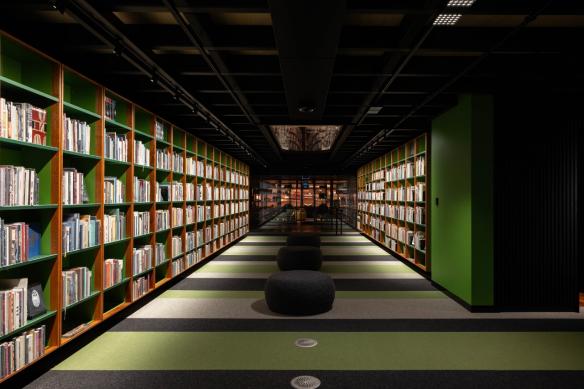 Rows of books sit on long shelves lining the walls of a cave-like library. © MONA/Jesse Hunniford