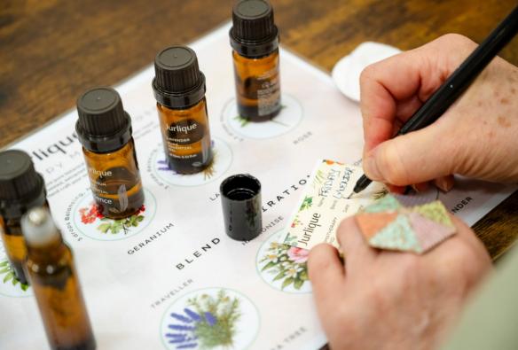 A close up of a person writing on a scent card, describing a freshly made botanical oil blend. © Beyond Wellness Co & Jurlique 