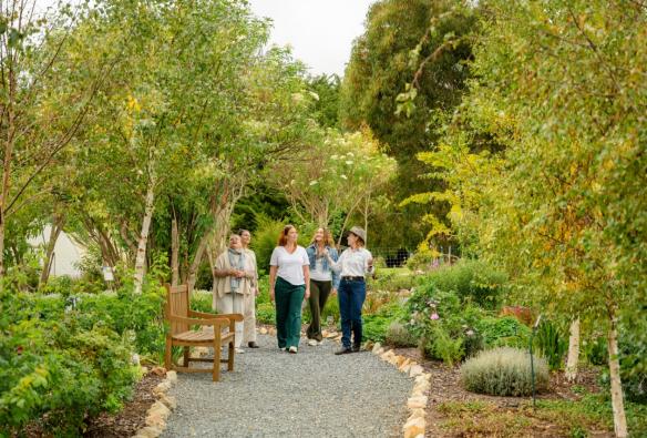 A guide walks with a small group along a paved path, through a botanical garden. © Beyond Wellness Co & Jurlique