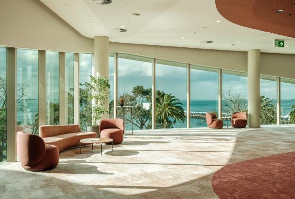 A carpeted foyer with chairs and glass panelling looks out onto a pretty bay. © Nic Stephens / Nyaal Banyul Geelong Convention and Event Centre