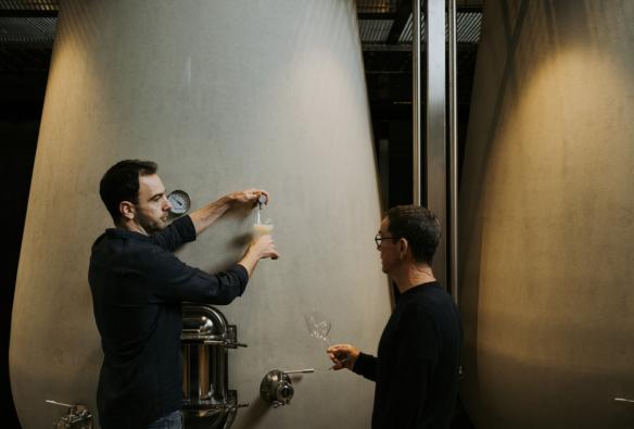 A winemaker draws a glass of wine from a cement tank that is used in the natural winemaking process. © Wayfinder Wines